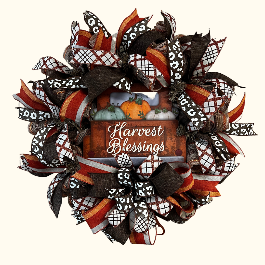 Harvest blessings deco mesh wreath of browns, tans and oranges. brown blaid ribbons, orange ribbons and brown and white animal print too. with a big beautiful bow under the sign which is placed right in the middle of the wreath.