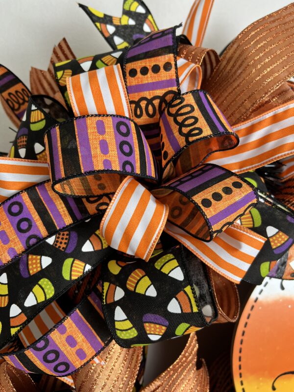 trick or treat halloween wreath with orange and purple ribbons, candy corn ribbons and a large trick or treat sign. This wreath has orange deco mesh as its base on a wire wreath frame. two big beautiful matching ribbon bows adorn this wreath.