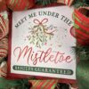 Christmas wreath with Meet me under the mistletoe sign placed in the middle of the wreath,red, green and white glittered ribbons, mistletoe ribbon with a large bow with the same ribbons adorn this wreath