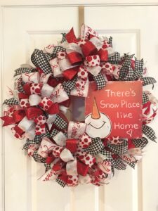 Winter wreath with Snow place like home sign, lots of red and white ribbons, let it snow ribbons and whimsical black and white ribbons, with a beautiful bow to match.