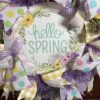 spring deco mesh wreath, hello spring sign, yellow and white plaid ribbon, purple and white gingham ribbon, spring colored polka dot ribbon, pastel spring colored striped ribbon, lavender and white plaid deco mesh base, lavender spring flowers