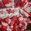 Valentine's day wreath, colors of reds and pink ribbons, Valentine sign with red and pink haearts on white background, large matching bow in red and pink ribbons adorn the wreath